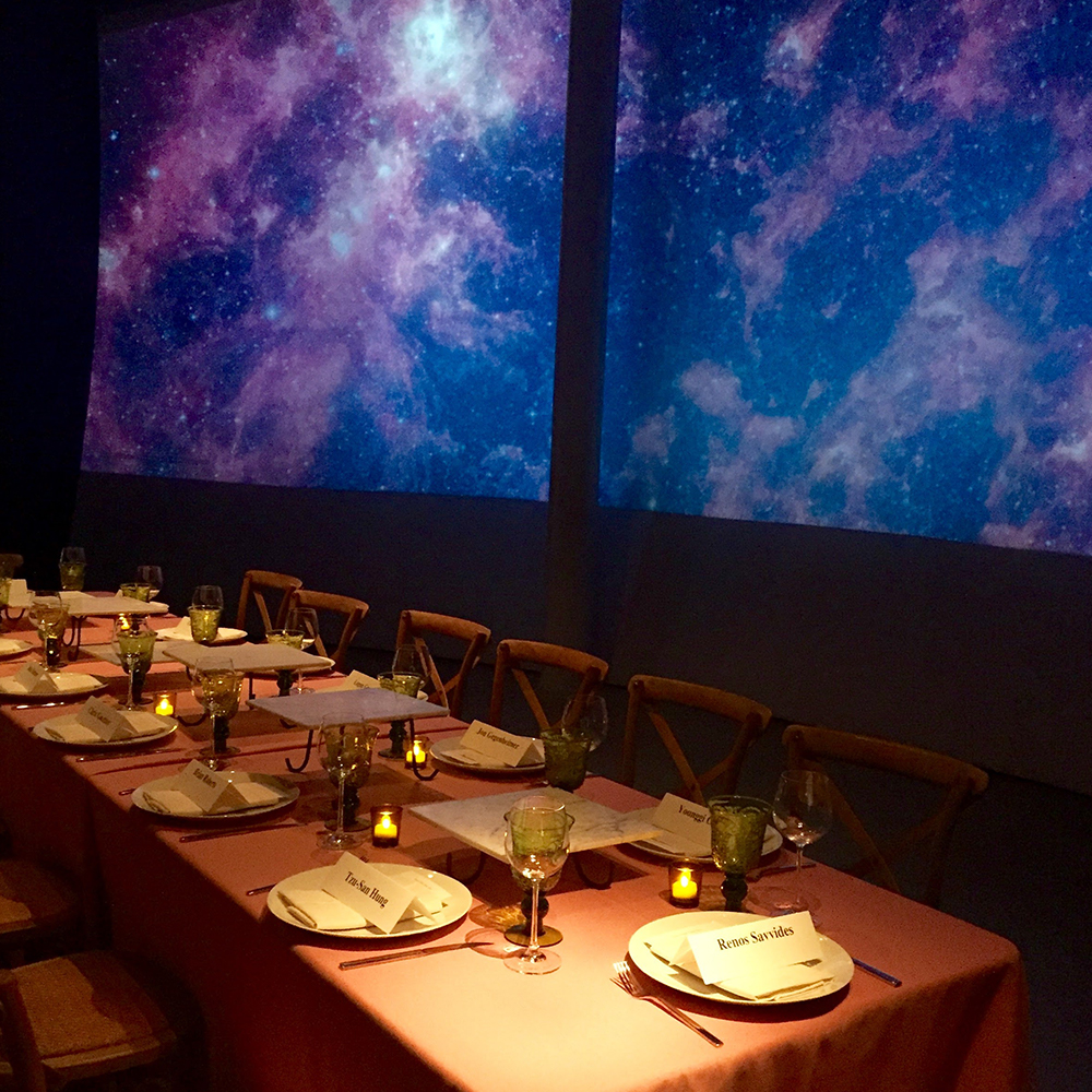 Event with long table surrounded by projection screens