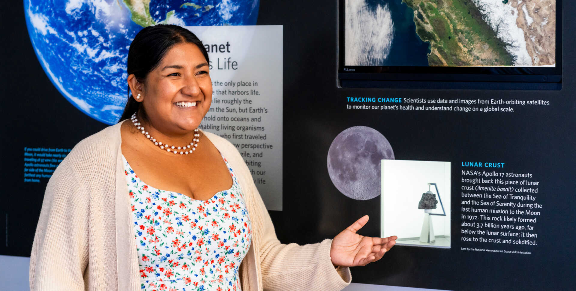 Academy geology collections manager Crystal Cortez stands next to the Moon rock display at the museum