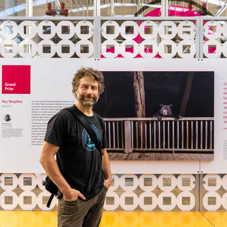 BigPicture 2023 Grand Prize winner Corey Arnold poses with the winning image on exhibit at the Academy