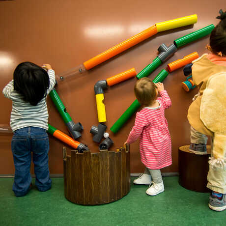 Kids playing with the colorful wall puzzle in the new Curiosity Grove