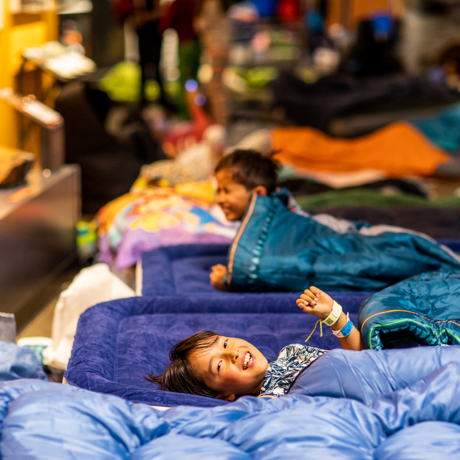 Children laying in sleeping bags in an exhibit area