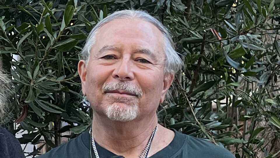 A profile shot of Gregg Castro, against a green backdrop. 