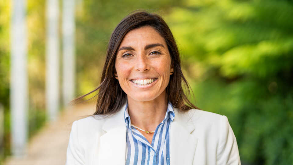 Estefanía Pihen González is pictured outdoors in a white blazer and blue blouse.