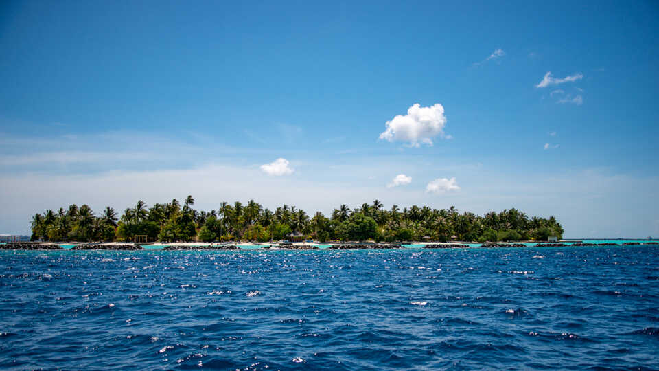 Atoll in Maldives with blue sky and white clouds